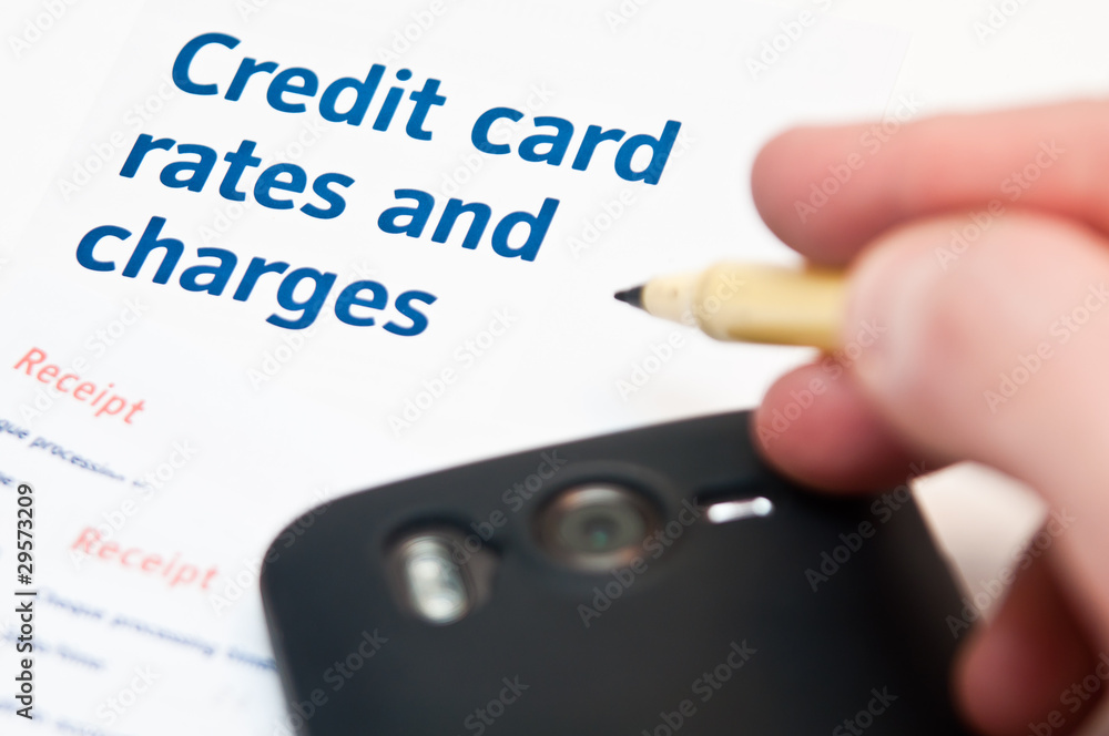 Hand holding pen over cedit card rates Hand holding pen over cedit card rates
