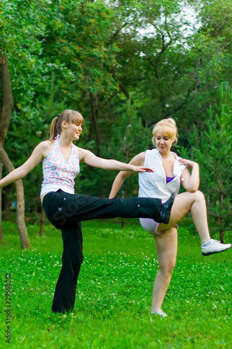 two women doing yoga in park