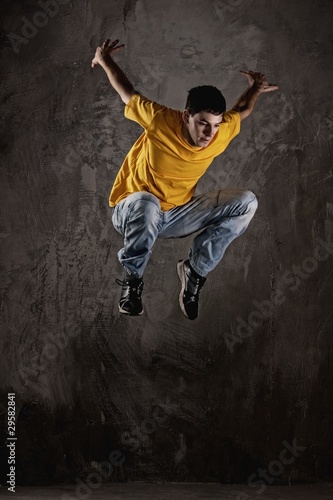 Young man jumping against grunge wall