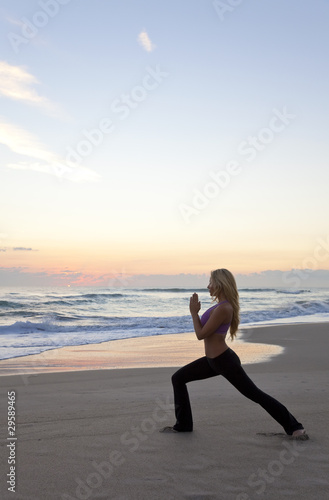 Beautiful Woman Practicing Yoga on Beach At Sunrise or Sunset