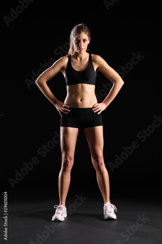 Fit young woman standing in black sports outfit