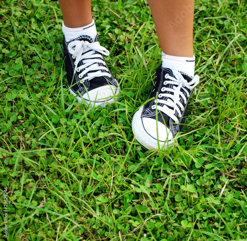 feet of the child of the teenager in gym shoes on a grass