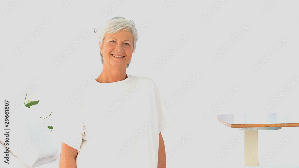 Retired woman looking at the camera in a white living room Retired woman looking at the camera in a white living room