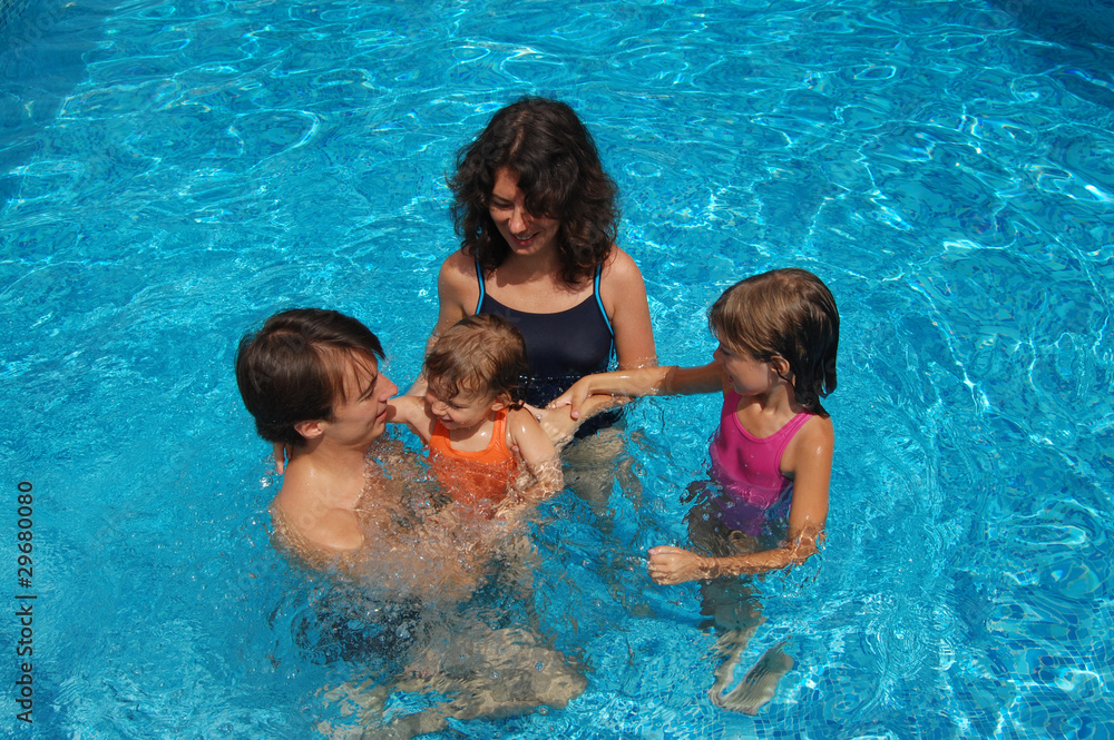 Happy family with two kids having fun in swimming pool