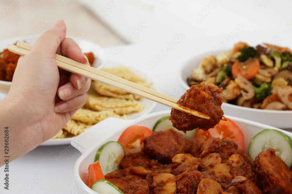 Hand holding a piece of chicken meat with chopsticks