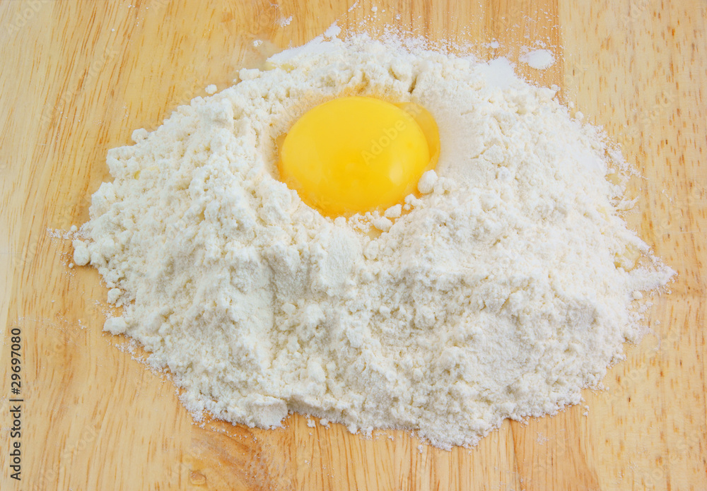Egg yolk on flour on wooden background Egg yolk on flour on wooden background