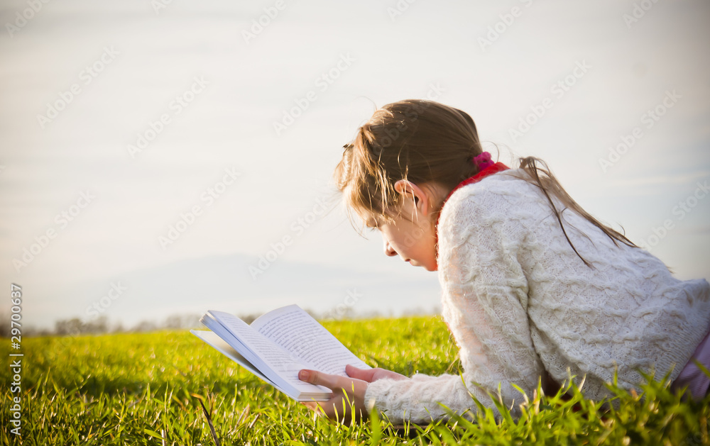 Girl reading a book on the grass