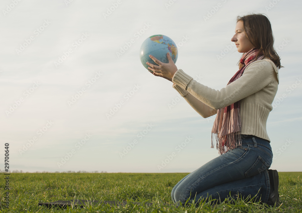 Teen girl sitting with a globe on the grass