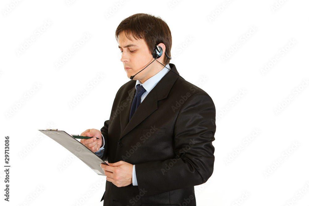 Serious businessman with headset checking notes in document Serious businessman with headset checking notes in document