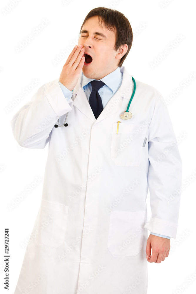Tired young medical doctor yawning isolated. Tired young medical doctor yawning isolated.