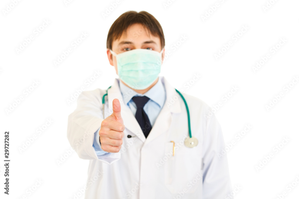 Medical doctor with mask on face showing  thumbs up gesture