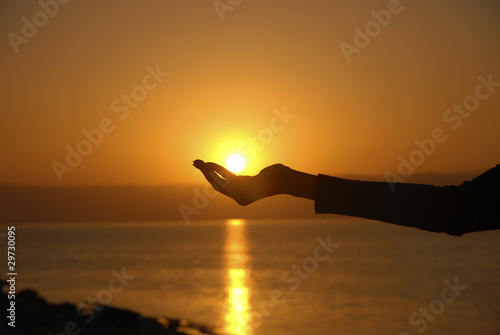 Hand holding the sun in the dead Sea