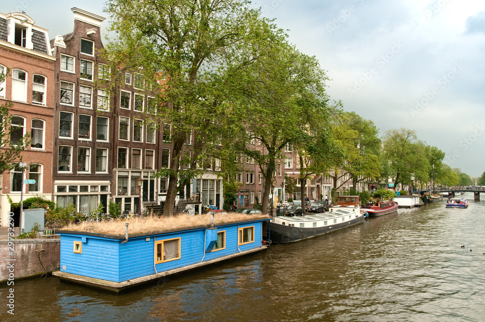 Typical Amsterdam's canal with blue house boat (houseboat)