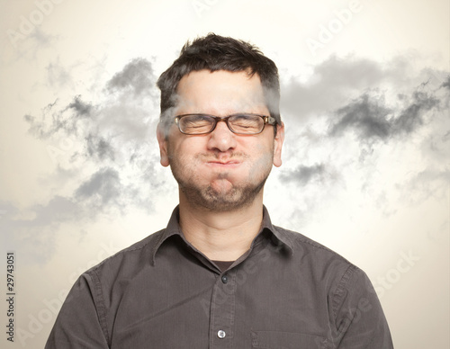Young man holding his breath among black clouds