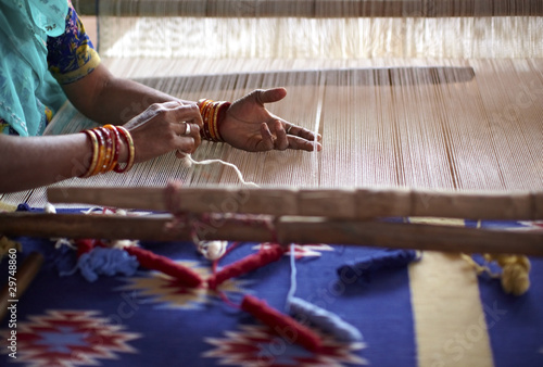 Woman hand weaving a carpet with a manual loom in India photo