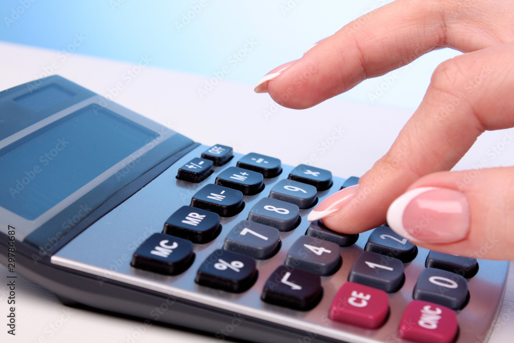 Fingers and calculator on blue background Fingers and calculator on blue background