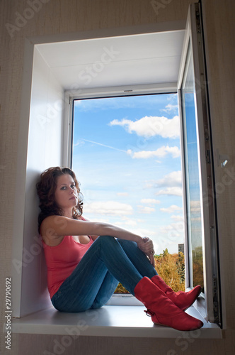 Girl in red boots sitting on a windowsill