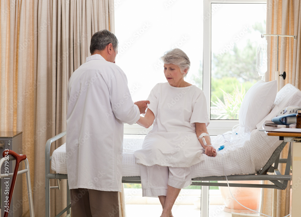 Fototapeta premium Mature doctor taking the blood pressure of his patient
