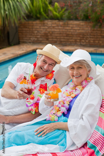 Mature couple drinking a cocktail  beside the swimming pool © WavebreakMediaMicro