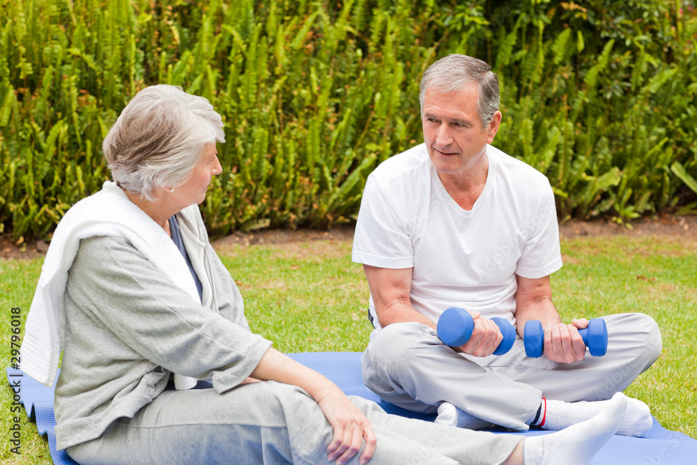 Mature couple doing their exercises in the garden Mature couple doing their exercises in the garden