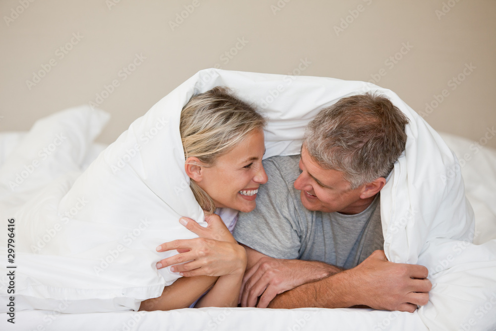 Couple lying down in their bed at home Couple lying down in their bed at home