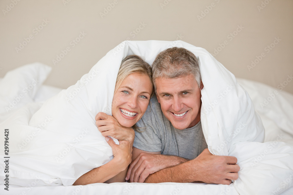 Couple lying down in their bed at home Couple lying down in their bed at home