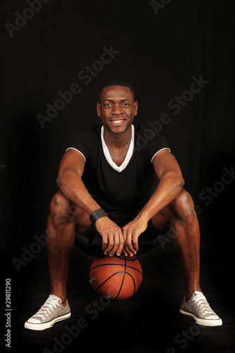 sportlicher Mann sitzt auf Basketball