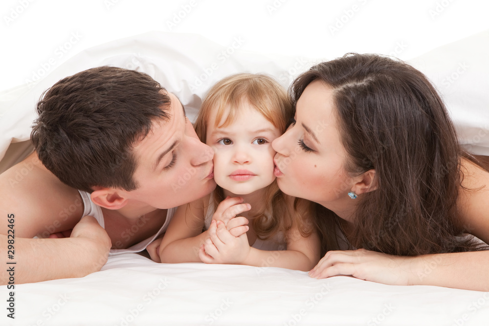 Happy family, mother, father and daughter on the white bed Happy family, mother, father and daughter on the white bed