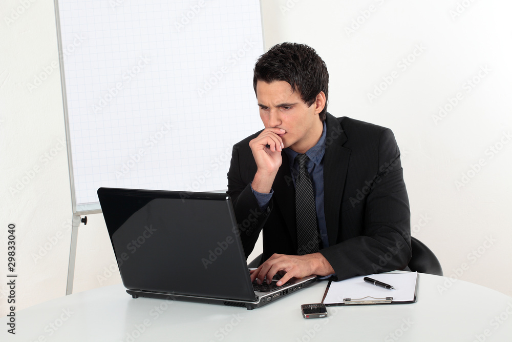 Junger Mann erfolgreich nachdenklich am Laptop Junger Mann erfolgreich nachdenklich am Laptop