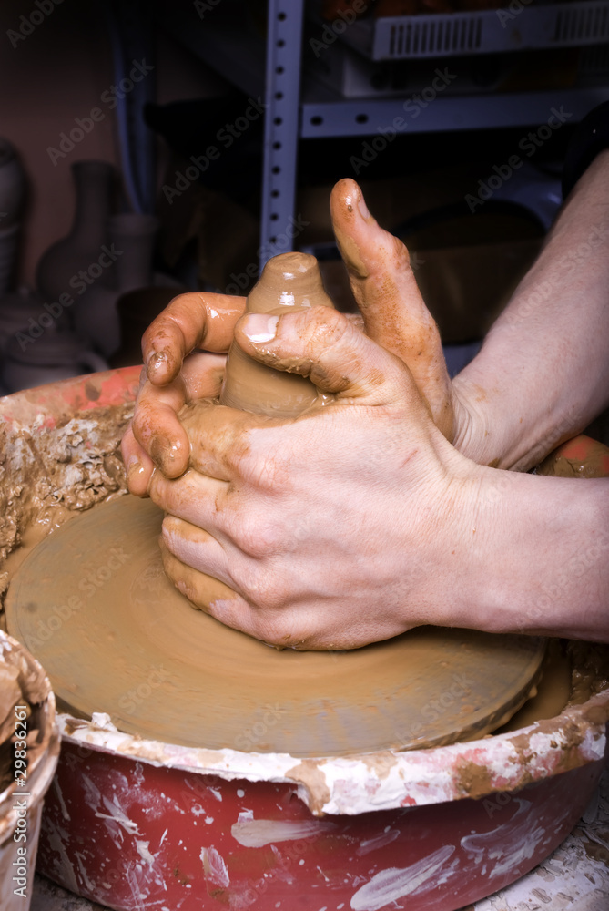 The hands of a potter, creating an earthen jar on the circle