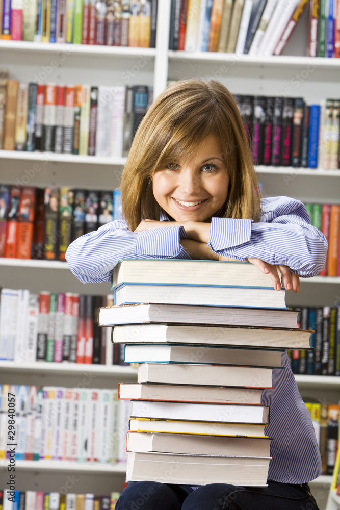 Young smilling woman sitting with books in the library Young smilling woman sitting with books in the library