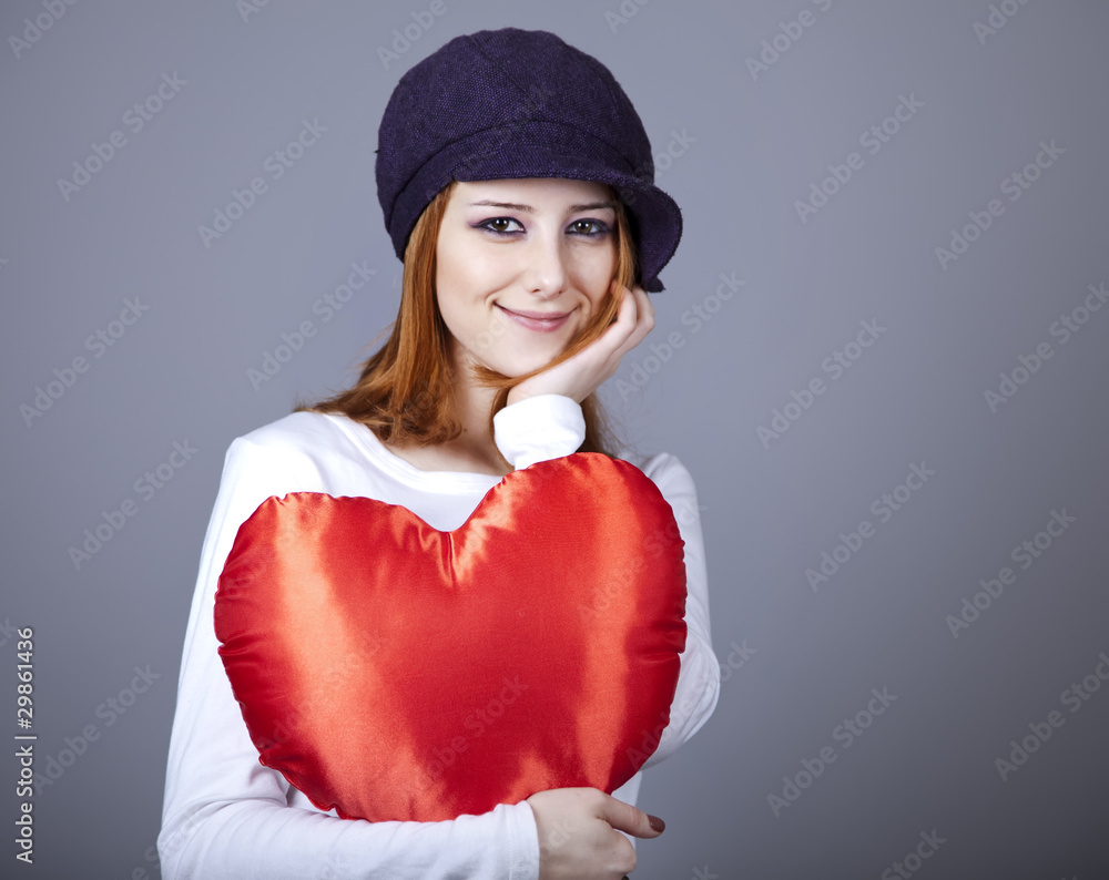 Beautiful red-haired girl in cap with toy heart. Beautiful red-haired girl in cap with toy heart.