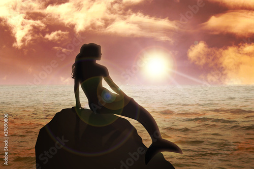A mermaid sitting on the rock during sunset