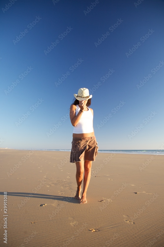 front woman with hat walking at beach - obrazy, fototapety, plakaty 