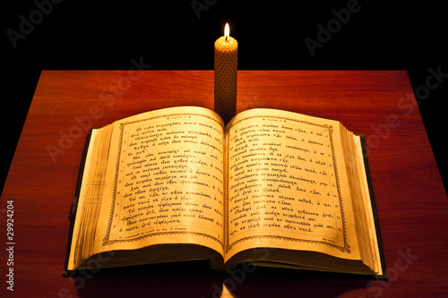 A bible open on a table next to a candle