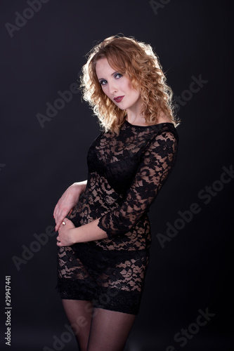 Young gorgeous model in a lace dress, a black background
