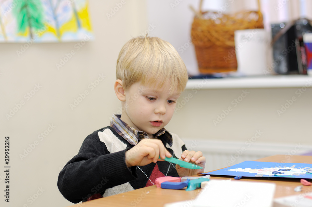 A little boy at the table molds from clay painting A little boy at the table molds from clay painting
