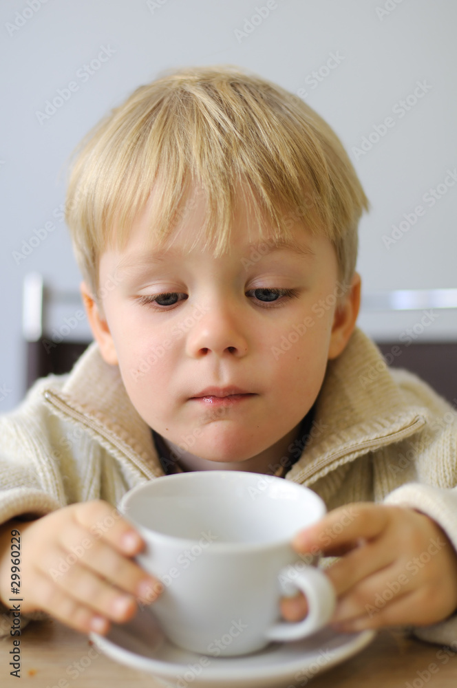 Little boy drinks tea and watch the cup Little boy drinks tea and watch the cup
