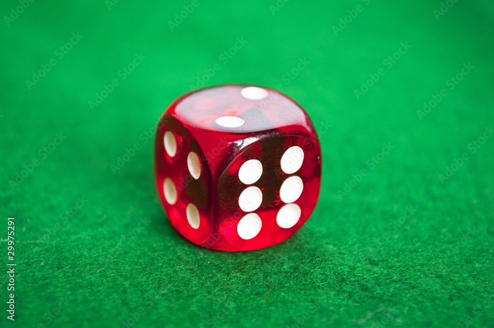 Single red dice on green background Single red dice on green background
