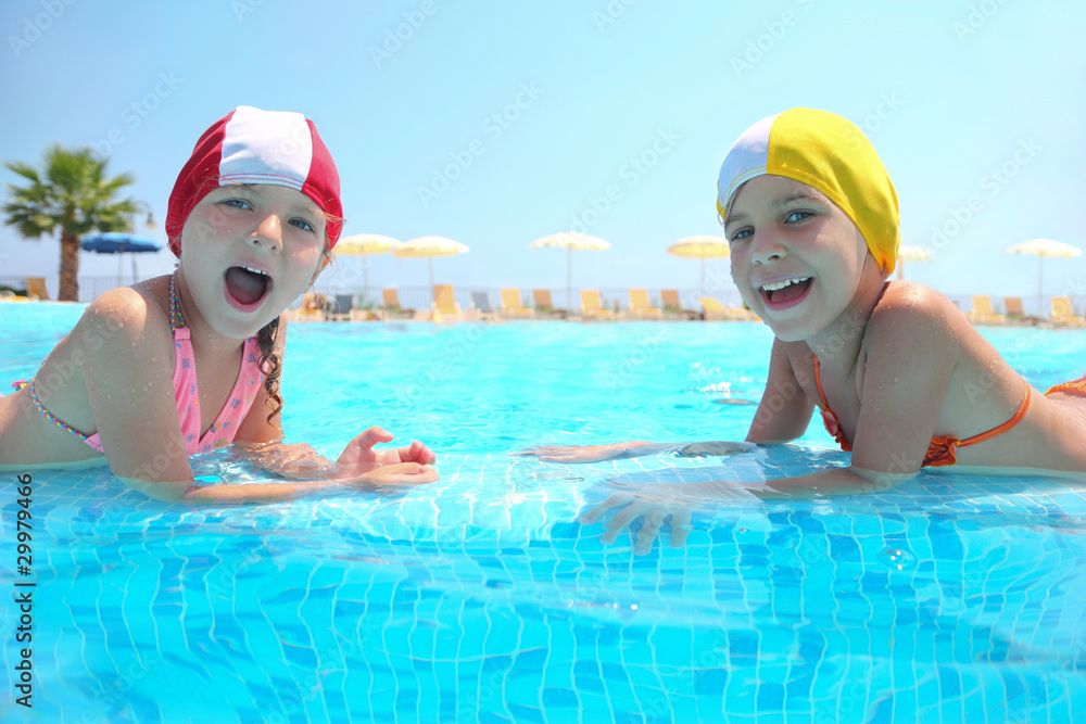 Two girls lie in  pool on skirting and laugh