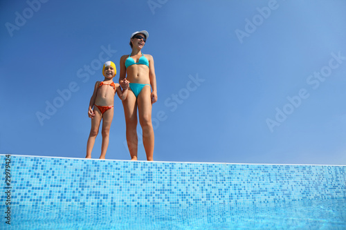 Obraz na plátně Girl with  mother stand on skirting of pool under open-skies