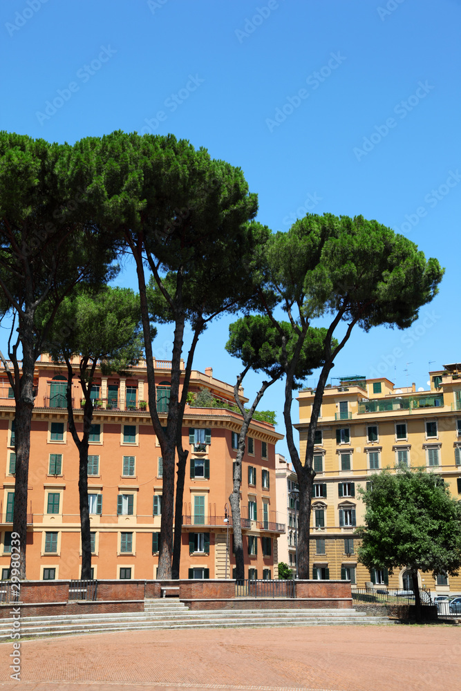 multi-storey yellow houses in Rome, high green trees, blue sky