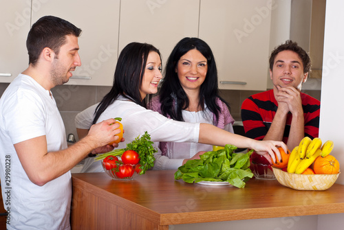 Happy friends in kitchen with vegetables