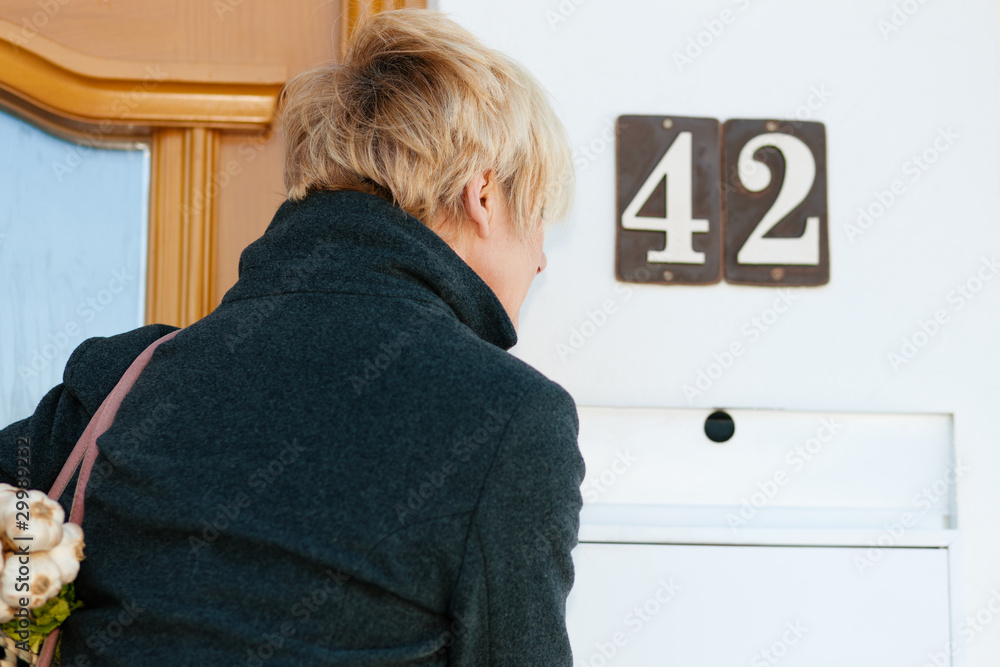 Frau schaut in den Briefkasten Frau schaut in den Briefkasten