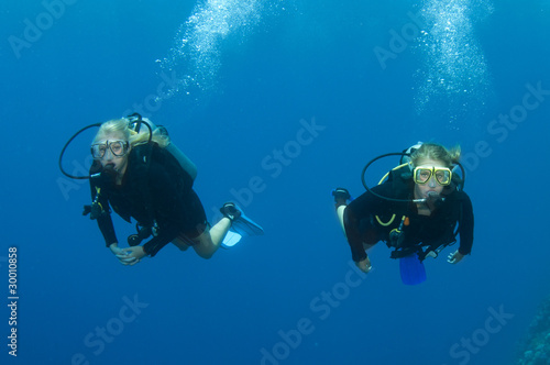 blond female scuba divers swim together