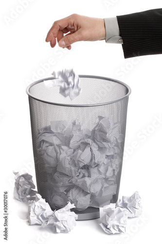 Hand dropping paper into wastepaper bin