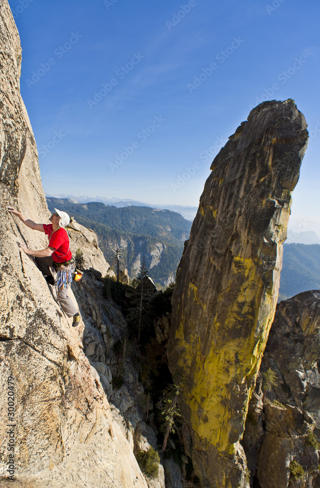 Naklejka premium Rock climber clinging to a cliff.