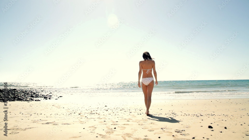 Sexy woman in white bikini walking in to the sea Sexy woman in white bikini walking in to the sea