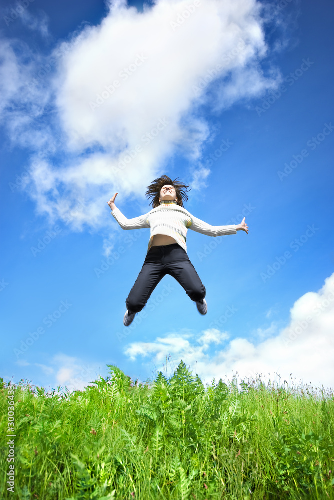 Young woman jumping into the field against the blue sky Young woman jumping into the field against the blue sky