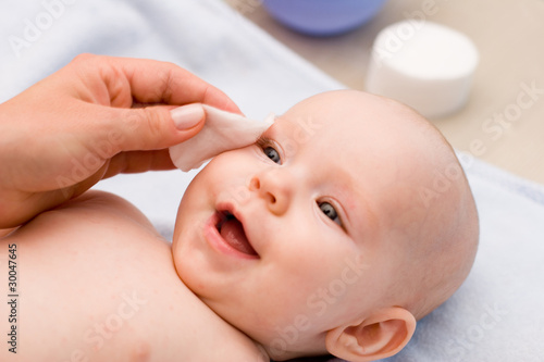 cleaning baby 's eye with cotton pad photo